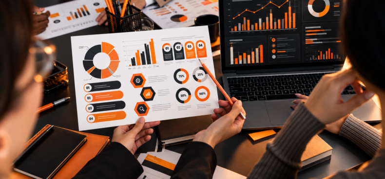 Team comparing printed marketing reports with a laptop analytics dashboard